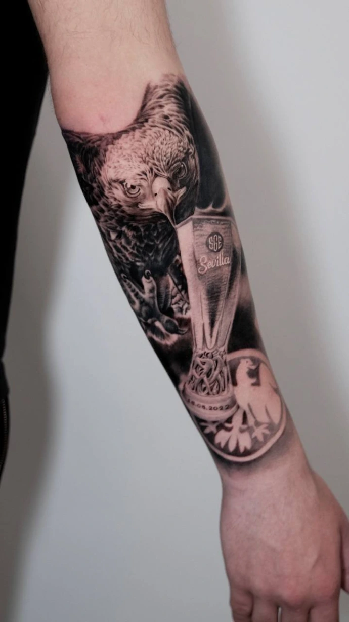 Schwarz-Weiß-Tattoo mit Adler, Europa-League-Pokal und Eintracht-Frankfurt-Logo am Unterarm von Experten in Friedberg, Frankfurt am Main und Hanau.