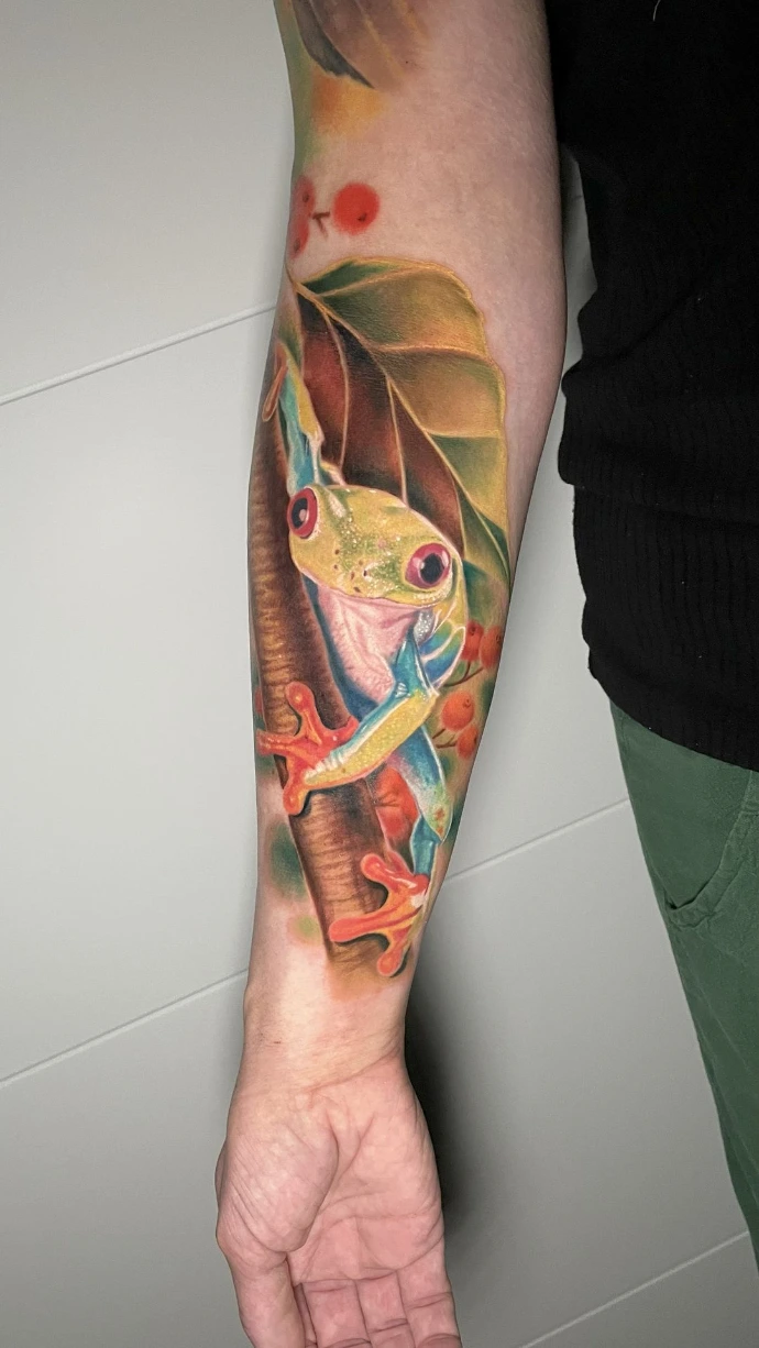 Dieses detailreiche Unterarm-Tattoo im Farbrealismus setzt den exotischen Rotaugenlaubfrosch mit höchster Präzision und lebendiger Farbtiefe in Szene und unterstreicht die kunstvolle Umsetzung naturnaher Motive