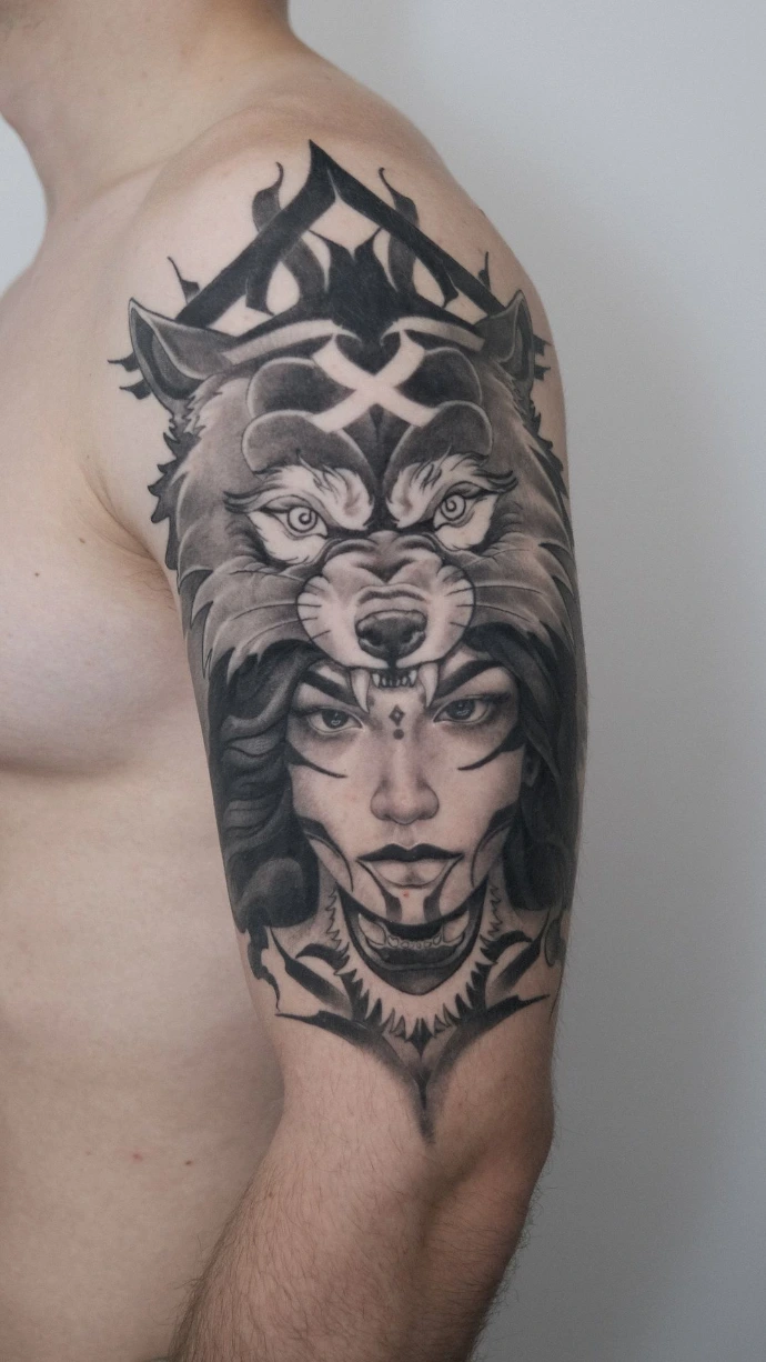 Dieses ausdrucksstarke Black-and-Grey Neo-Traditional Tattoo am Oberarm kombiniert klassische Porträtkunst mit markanten, modernen Elementen. Das Motiv zeigt eine Frau mit einer Wolfskopf-Kopfbedeckung, das durch seine klaren Linien, tiefen Schwarzanteile und die typische Neo-Trad-Symmetrie besticht. Die Verbindung von feinen Gesichtszügen und kräftigen, grafischen Ornamenten im Hintergrund verleiht diesem Kunstwerk eine zeitlose Ästhetik und eine starke, mystische Präsenz auf der Haut.