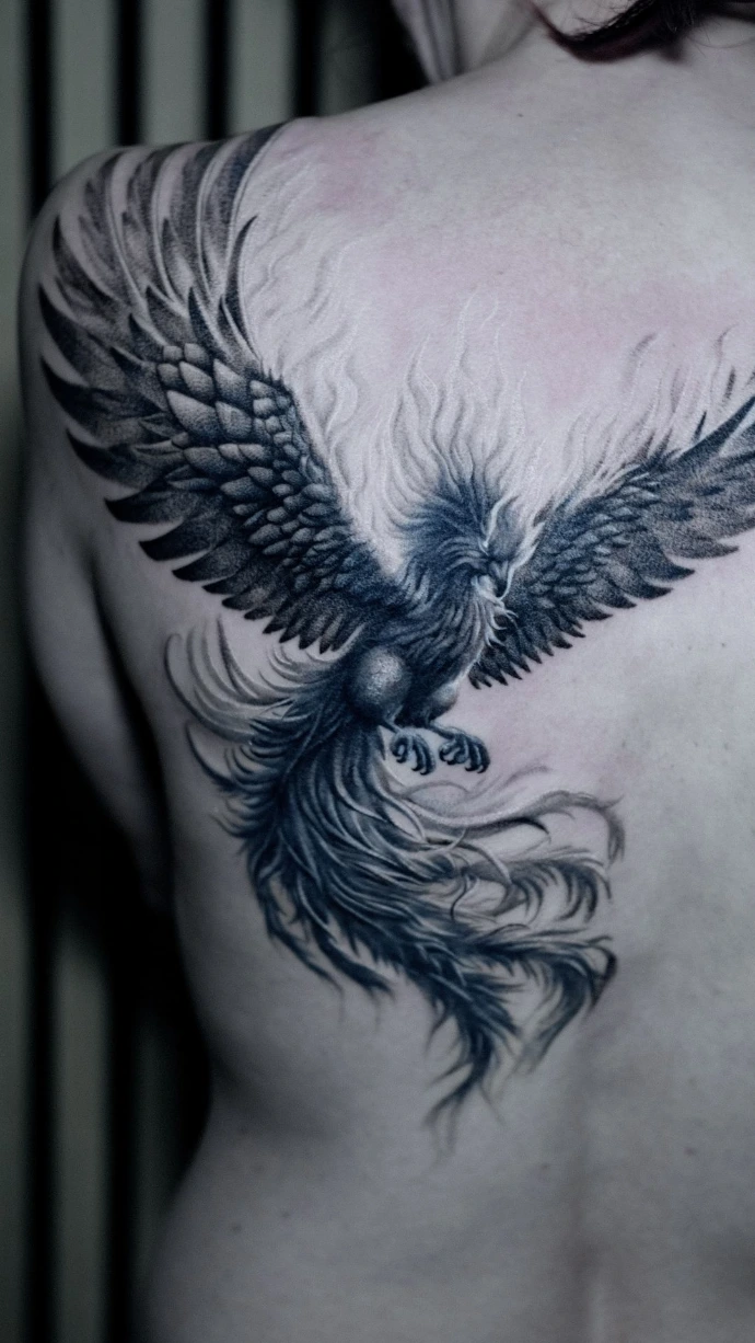 Dein exklusives Phönix-Realismus Tattoo auf dem Rücken in Friedberg, Hanau und Frankfurt am Main – book your professional black and grey back piece session now. Realistic Black and Grey Phoenix Back Tattoo with Spreading Wings in Friedberg Hanau Frankfurt am Main